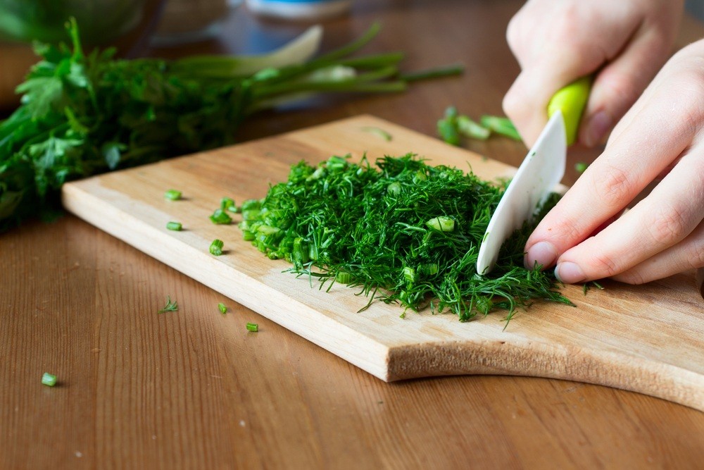 hachage d'herbe aromatiques sur une planche à découper avec un couteau ceramique
